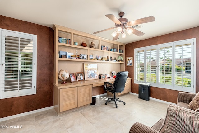 tiled office space with ceiling fan and built in desk