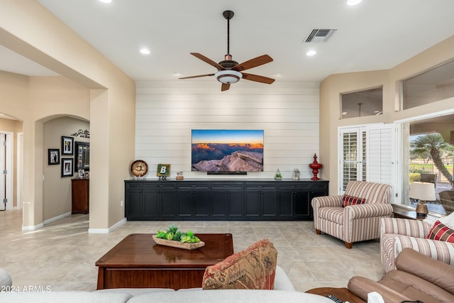 living room featuring ceiling fan and wood walls