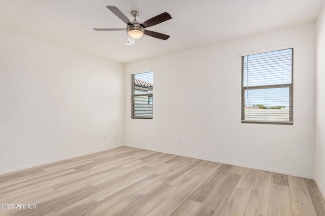 empty room featuring baseboards, light wood finished floors, and ceiling fan