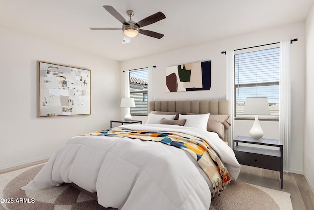 bedroom with a ceiling fan, baseboards, and light wood-style floors