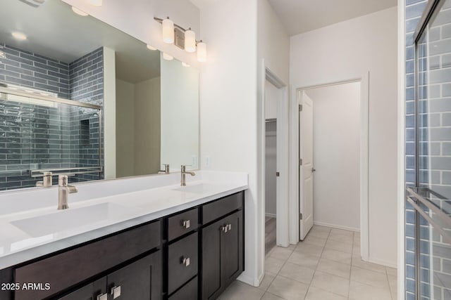 full bathroom featuring a shower stall, a spacious closet, tile patterned flooring, and a sink