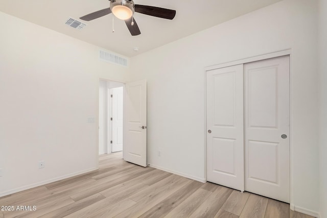 unfurnished bedroom with a closet, baseboards, visible vents, and light wood-type flooring