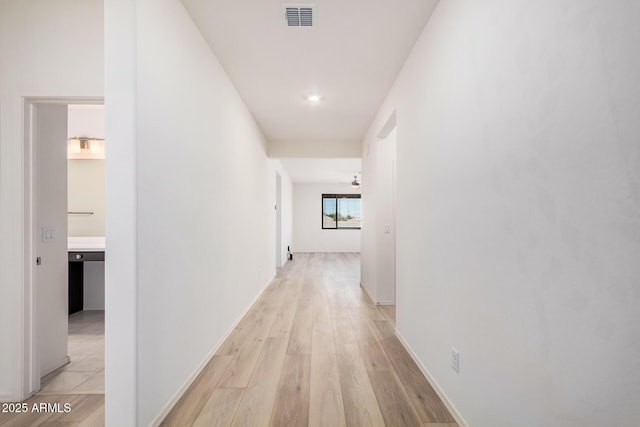corridor with baseboards, visible vents, and light wood-type flooring