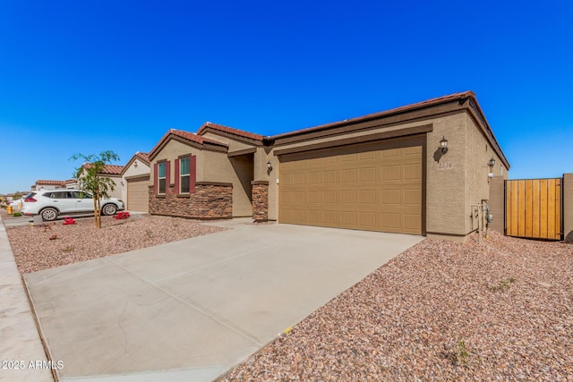 single story home featuring a gate, a garage, concrete driveway, a tile roof, and stucco siding