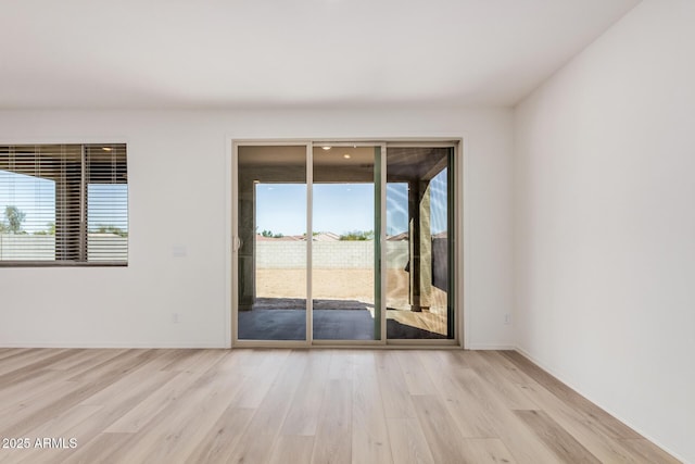 spare room featuring baseboards and light wood finished floors