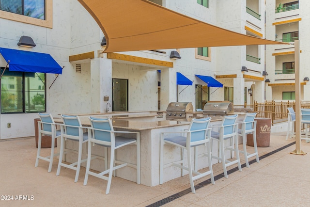 view of terrace featuring a grill, a bar, and a balcony