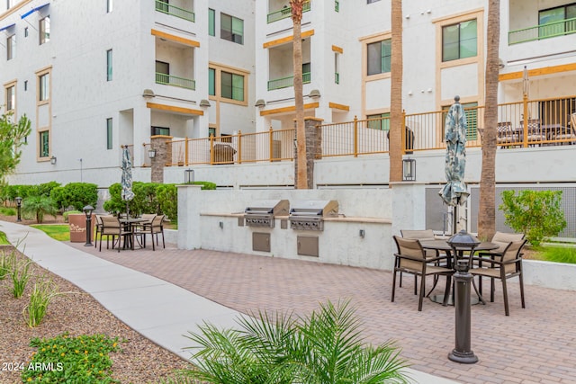 view of terrace with a balcony, grilling area, and an outdoor kitchen