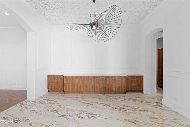 3354 E Jaeger Cir, Mesa, AZ 85213 - unfurnished room featuring light marble finish flooring, ornamental molding, arched walkways, a decorative wall, and a chandelier