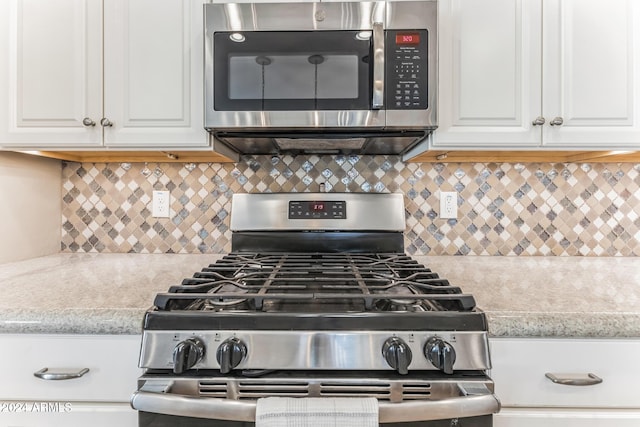 room details featuring white cabinets, light stone counters, stainless steel appliances, and tasteful backsplash