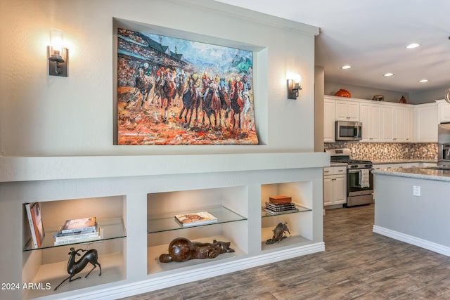 kitchen with tasteful backsplash, dark hardwood / wood-style flooring, white cabinets, and appliances with stainless steel finishes