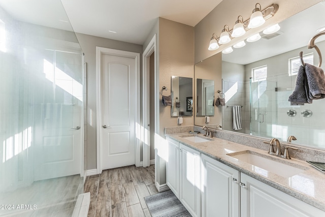 bathroom with wood-type flooring, vanity, and a shower with door