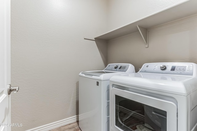 clothes washing area with separate washer and dryer and light hardwood / wood-style flooring