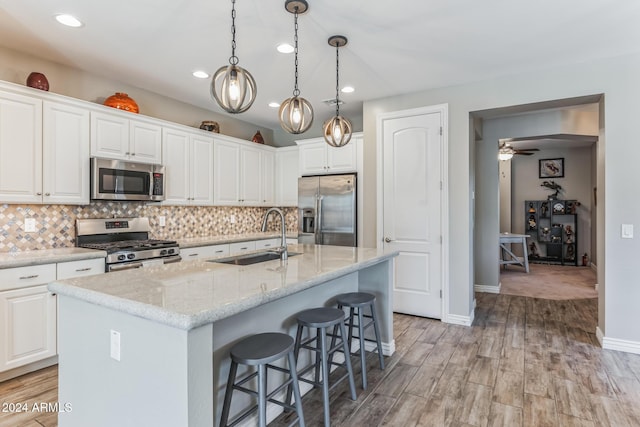 kitchen with a center island with sink, sink, white cabinetry, and stainless steel appliances