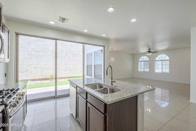 3451 S Wren Dr, Gilbert, AZ 85297 - kitchen with stainless steel range with gas stovetop, a ceiling fan, dark brown cabinetry, light tile patterned flooring, and recessed lighting