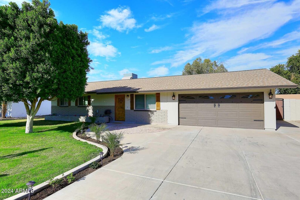 ranch-style home with a garage and a front lawn