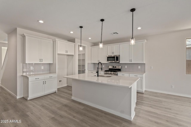 kitchen featuring white cabinetry, sink, appliances with stainless steel finishes, and an island with sink