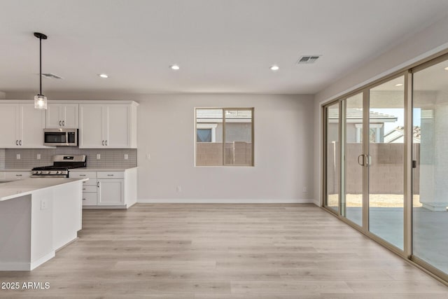 kitchen featuring stainless steel appliances, tasteful backsplash, light hardwood / wood-style flooring, pendant lighting, and white cabinets