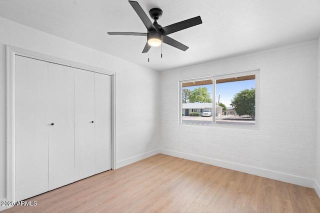 11220 N 109th Ave, Sun City, AZ 85351 - unfurnished bedroom with baseboards, light wood finished floors, a closet, brick wall, and ceiling fan