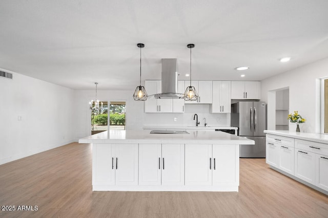 11220 N 109th Ave, Sun City, AZ 85351 - kitchen with freestanding refrigerator, island range hood, light countertops, light wood-style floors, and white cabinets