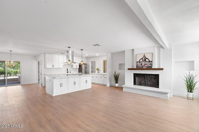 11220 N 109th Ave, Sun City, AZ 85351 - unfurnished living room with light wood-style floors, a chandelier, a fireplace with raised hearth, baseboards, and a sink