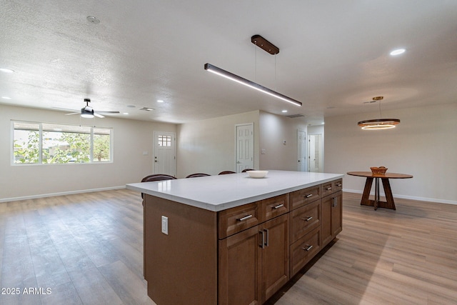 1210 W La Jolla Dr, Tempe, AZ 85282 - kitchen with open floor plan, light wood finished floors, a kitchen island, recessed lighting, and light countertops