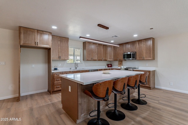 1210 W La Jolla Dr, Tempe, AZ 85282 - kitchen featuring stainless steel appliances, light wood-type flooring, a kitchen island, a kitchen breakfast bar, and recessed lighting