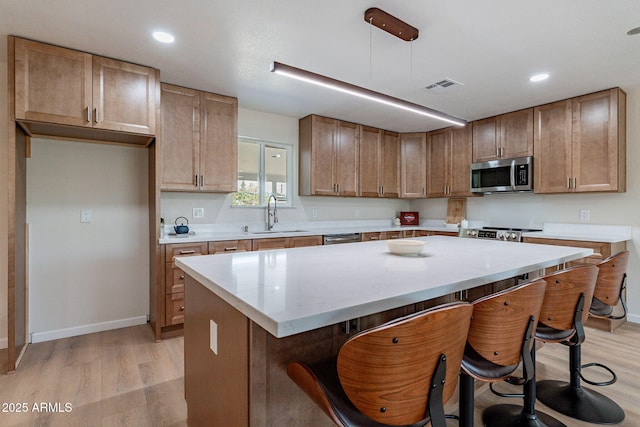 1210 W La Jolla Dr, Tempe, AZ 85282 - kitchen with appliances with stainless steel finishes, light wood-type flooring, a kitchen bar, a center island, and recessed lighting