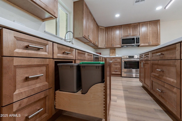 1210 W La Jolla Dr, Tempe, AZ 85282 - kitchen featuring stainless steel appliances, light wood finished floors, recessed lighting, brown cabinetry, and light countertops