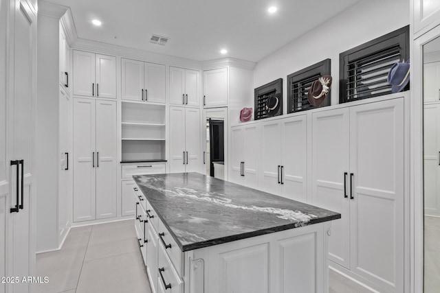 kitchen with visible vents, a kitchen island, dark stone countertops, white cabinetry, and open shelves