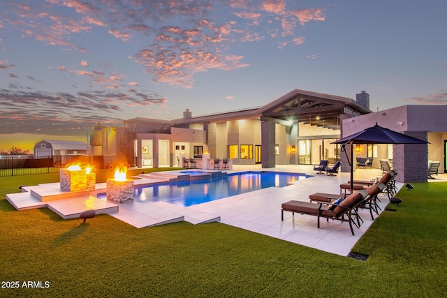 view of swimming pool featuring a patio area, a pool with connected hot tub, an outdoor fire pit, and a yard