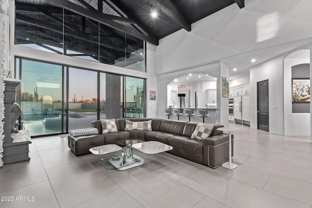 living room featuring light tile patterned floors, high vaulted ceiling, beam ceiling, arched walkways, and wood ceiling