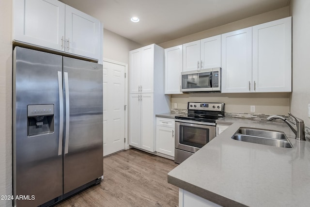 kitchen with sink, white cabinets, light hardwood / wood-style flooring, and appliances with stainless steel finishes