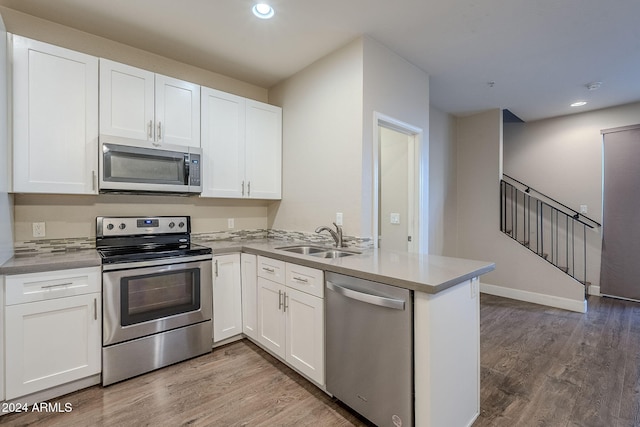 kitchen featuring kitchen peninsula, appliances with stainless steel finishes, white cabinets, and sink