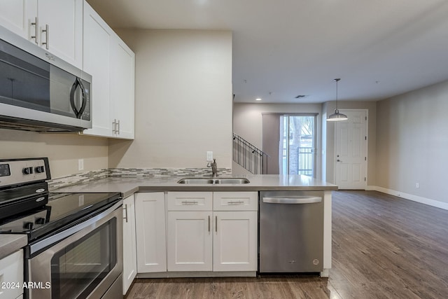 kitchen with white cabinets, wood-type flooring, stainless steel appliances, and pendant lighting