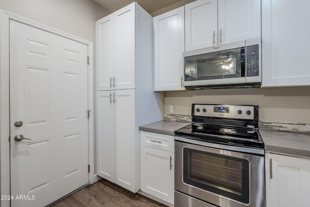 kitchen with white cabinets, appliances with stainless steel finishes, and dark hardwood / wood-style flooring