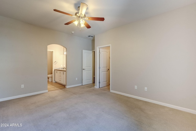 unfurnished bedroom with ceiling fan, light carpet, and connected bathroom