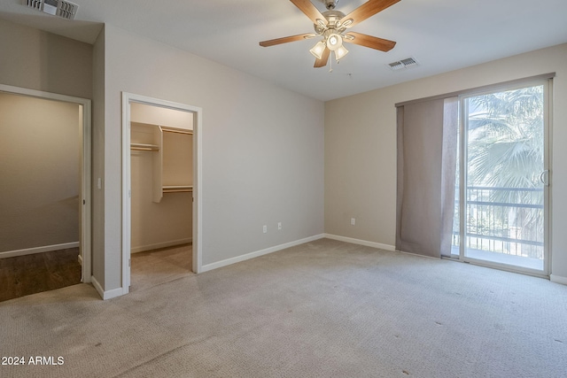 unfurnished bedroom with light carpet, a closet, a spacious closet, and ceiling fan