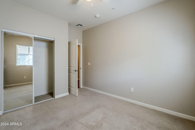 unfurnished bedroom featuring a closet, ceiling fan, and light colored carpet