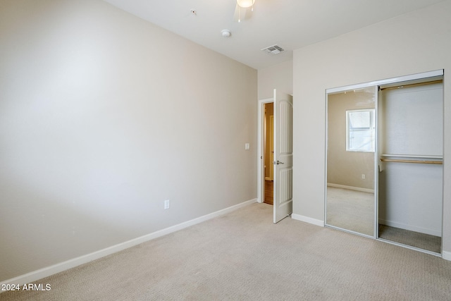 unfurnished bedroom featuring ceiling fan, light carpet, and a closet