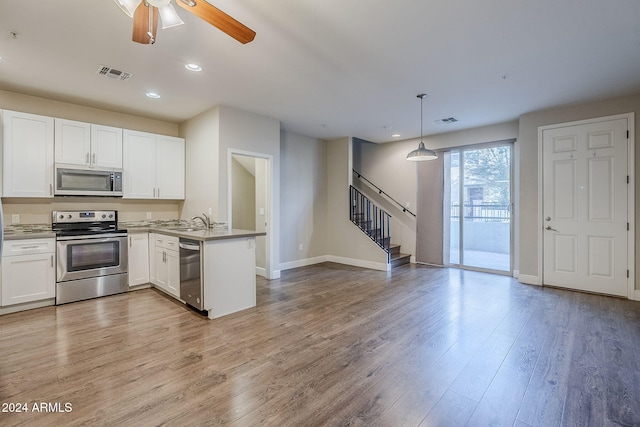 kitchen featuring white cabinetry, stainless steel appliances, kitchen peninsula, pendant lighting, and light hardwood / wood-style floors