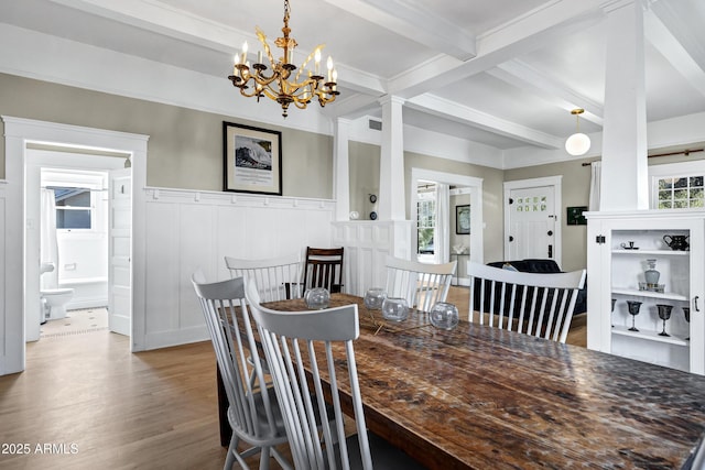 dining room with a wealth of natural light, a wainscoted wall, beam ceiling, and wood finished floors