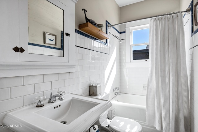 bathroom with shower / tub combo, decorative backsplash, toilet, a sink, and tile walls