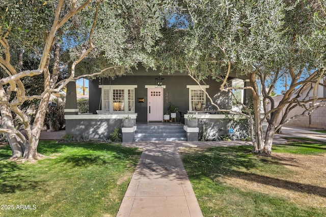 view of front of house featuring stucco siding, a porch, and a front yard