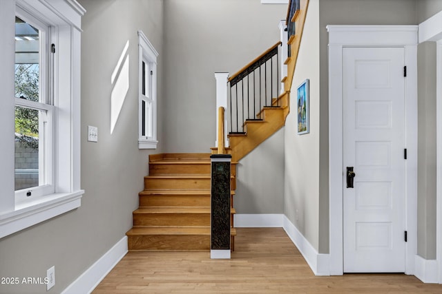 entrance foyer with light wood finished floors, stairway, and baseboards