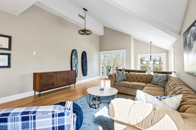 living area with high vaulted ceiling, wood finished floors, visible vents, and baseboards