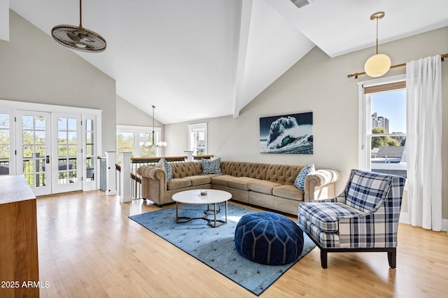 living area with visible vents, high vaulted ceiling, wood finished floors, and french doors