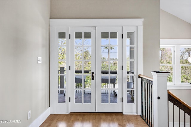 entryway featuring vaulted ceiling, french doors, wood finished floors, and baseboards