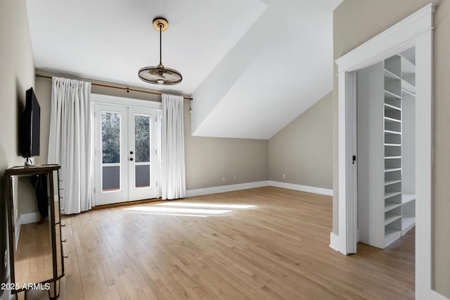 additional living space with light wood-style floors, french doors, vaulted ceiling, and baseboards