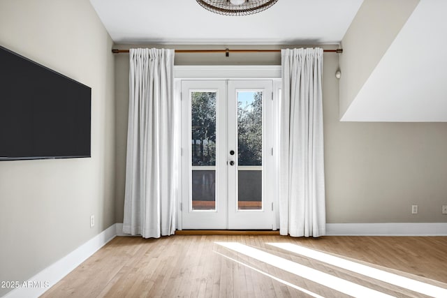 doorway to outside featuring baseboards, wood finished floors, and french doors