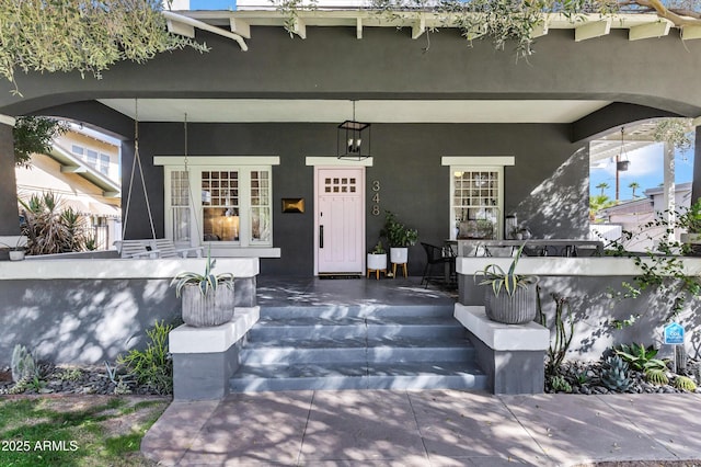 entrance to property with a porch and stucco siding